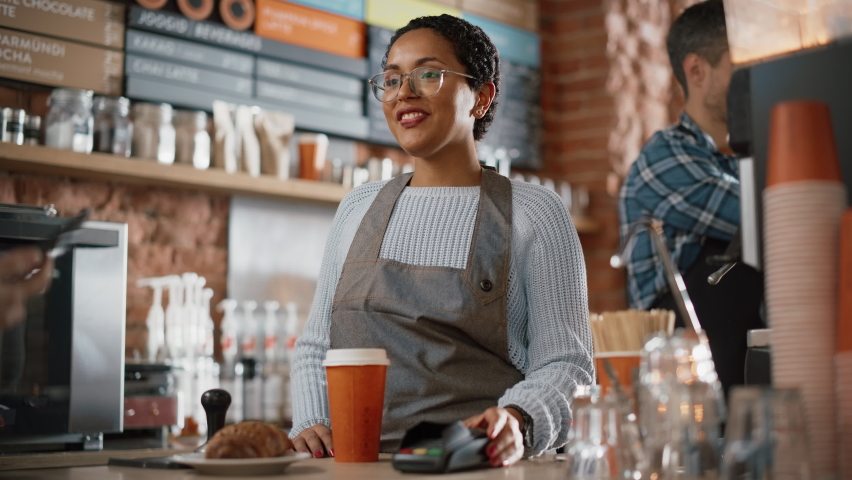 Joyful Multiethnic Diverse Woman Gives a Payment Terminal to Customer Using NFC Technology on Smartphone. Customer Uses Mobile to Pay for Take Away Latte and Pastry to a Barista in Coffee Shop. Royalty-Free Stock Footage #1062437233