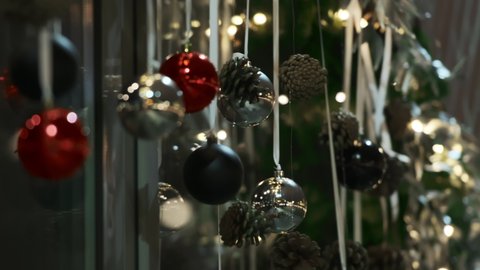 Christmas decoration with black, silver and red balls. Christmas cones hang on strings. The city is preparing for the New Year and Christmas holidays. Bokeh. City lights. Close up. 