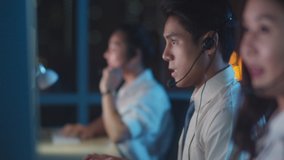 Millennial Asia young call center team or customer support service executive using computer and microphone headset working technical support in late night office. Telemarketing or sales job concept. - Powered by Shutterstock - Get 15% off with code: PIKWIZARD15