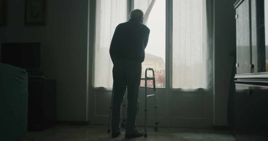 Cinematic shot of an elderly man is walking on stilts towards a window and opening a curtain to look outside . Concept of life, healthcare, retirement, disability, boarding house | Shutterstock HD Video #1062441691