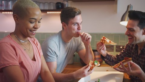 Male and female same sex couples meeting at home and eating takeaway pizza together - shot in slow motion