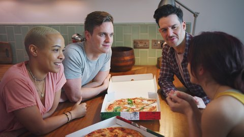 Male and female same sex couples meeting at home and eating takeaway pizza together - shot in slow motion