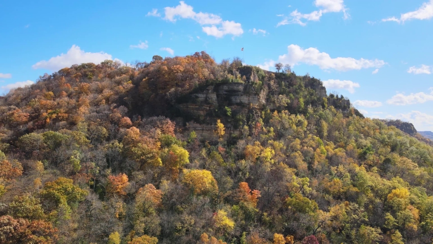 Colorful Fall Bluff with an American flag on the pole at the top of the mountain. Stunning aerial view of a house at the top of the mountain of Granddads Bluff in La Crosse, Wisconsin
