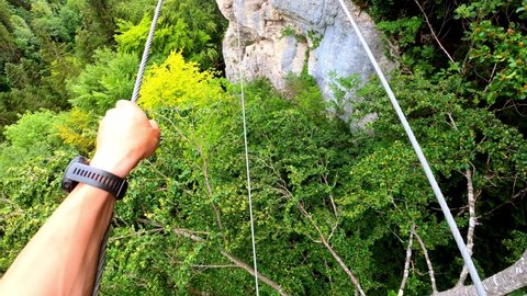 A man walking on a cable across a forest in France. Its the via ferrata "ladders of death" in France.
