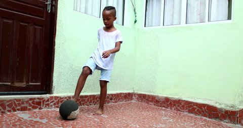 African child playing with ball, Black young boy kid plays sport by himself.