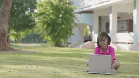Kids smiling and learning on laptop outside classroom in school, cute children sitting on grass filed, Asian child study by notebook for communication of data, kid use online for knowledge to learn