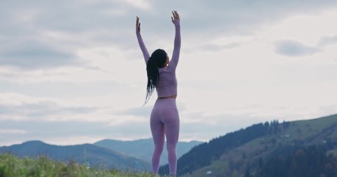 Shot back young African american woman doing yoga poses meditation in mountains. Harmony concentration activity nature healthy. Relaxation. Slow motion