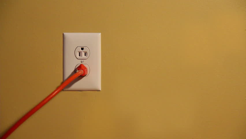 Close-up shot of a man plugging and unplugging an orange electrical cord into a
