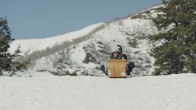 Slow motion of smiling women riding toboggan on snowy hill / Tibble Fork, Utah, United States