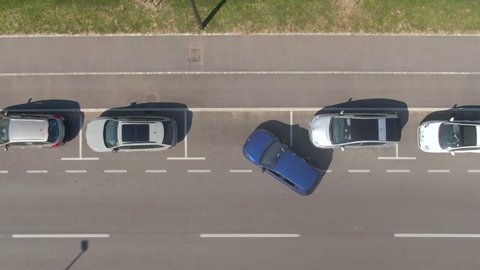 TIMELAPSE, AERIAL, TOP DOWN: Inexperienced driver is having problems parallel parking their car into a roadside parking space. Flying above person struggling to park vehicle into a row of parked cars.