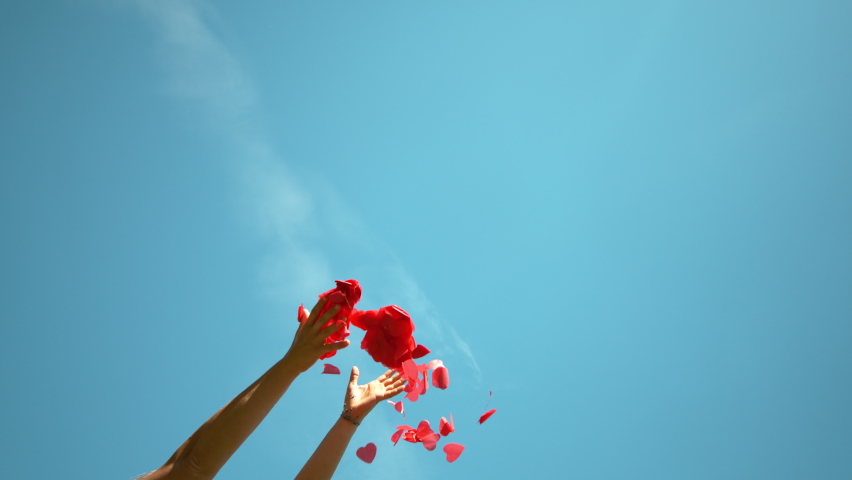 SLOW MOTION, BOTTOM UP: Unrecognizable person throws a handful of red confetti into the sky during a Valentine's day celebration. Woman tosses red heart shaped papers in air during baby gender reveal | Shutterstock HD Video #1062467431