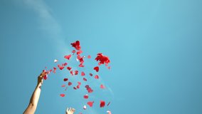 SLOW MOTION, BOTTOM UP: Unrecognizable person throws a handful of red confetti into the sky during a Valentine's day celebration. Woman tosses red heart shaped papers in air during baby gender reveal - Powered by Shutterstock - Get 15% off with code: PIKWIZARD15