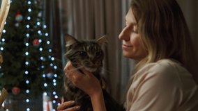 Mom strokes a beautiful cat. In the background, children play with the dog under the Christmas tree - Powered by Shutterstock - Get 15% off with code: PIKWIZARD15