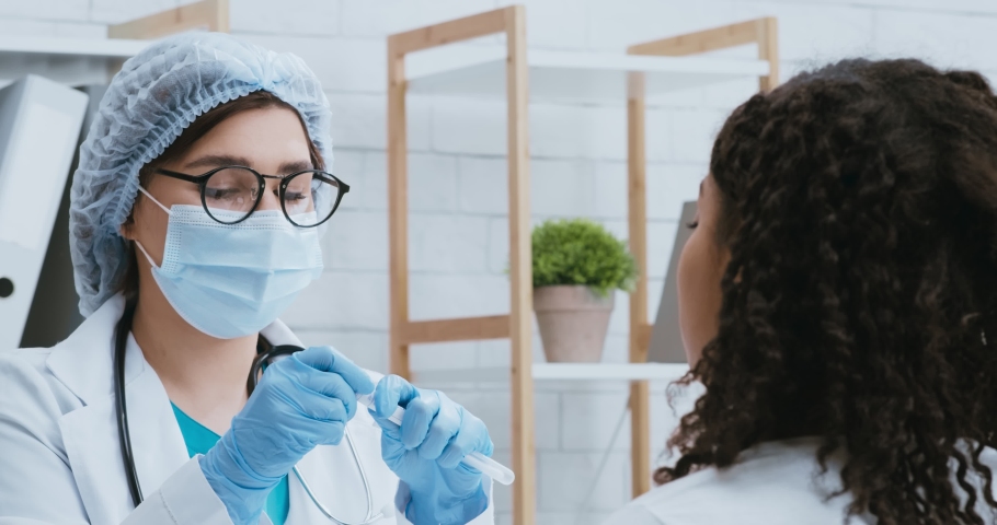 Covid-19 research. Doctor in protective mask taking pcr test sample from black woman with coronavirus symptoms Royalty-Free Stock Footage #1062471721