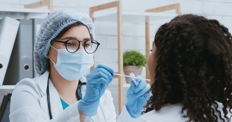 Covid-19 research. Doctor in protective mask taking pcr test sample from black woman with coronavirus symptoms | Shutterstock HD Video #1062471721