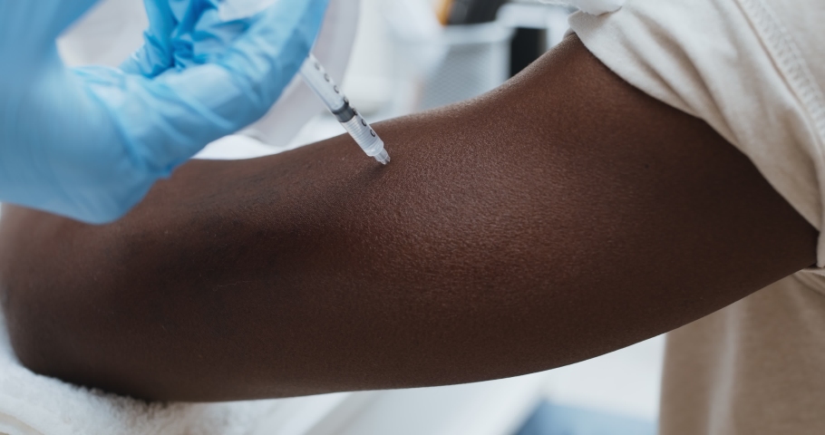 Adult black patient getting vaccine injection in hand at hospital, close up. Immunity stimulation to minimise risk of coronavirus infection. | Shutterstock HD Video #1062471805