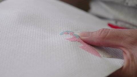 Close up of a ladies hands sewing cross stitch.