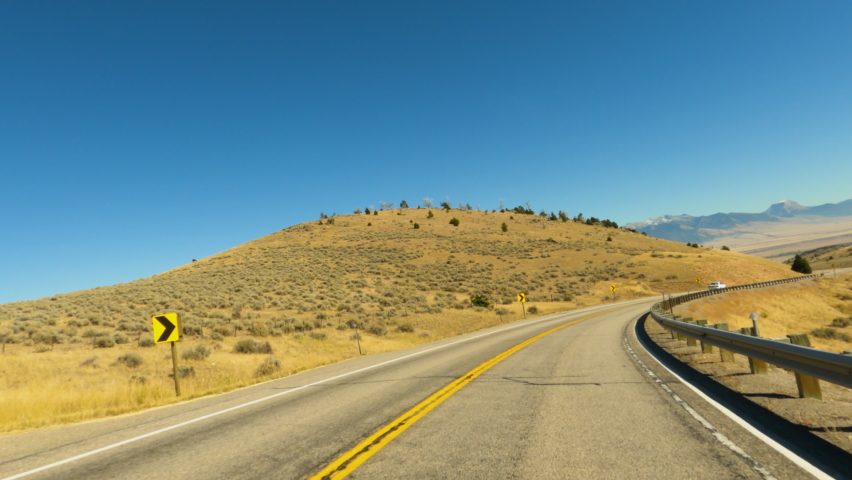 Rural Montana highway scenic drive into valley POV 4K. Along the Madison River in rural Montana near Yellowstone National Park. Originally a gold mining town. Tourism outdoor recreation destination.
