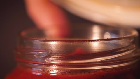 Opening glass jar of tomato sauce close up. Ingredient for meal like tomato pasta, spaghetti, traditional pizza. Vegetarian mediterranean recipe ingredient.
