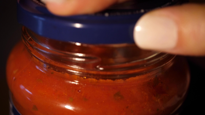Opening glass jar of tomato sauce close up. Ingredient for meal like tomato pasta, spaghetti, traditional pizza. Vegetarian mediterranean recipe ingredient. | Shutterstock HD Video #1062482092