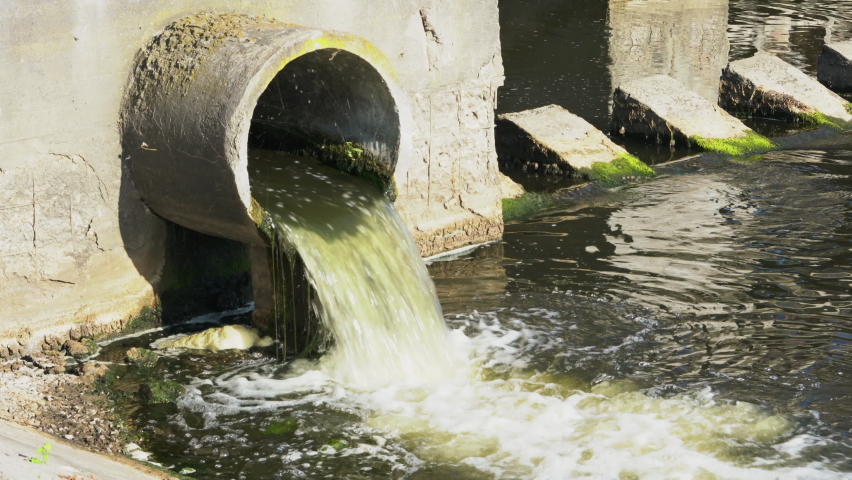 Dirty water flows from the pipe into the river, environmental pollution. Sewerage, treatment facilities | Shutterstock HD Video #1062487078
