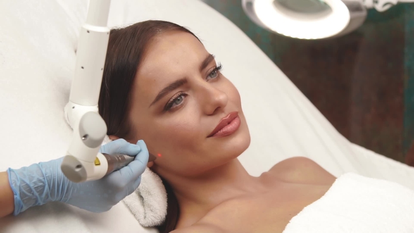 girl with perfect skin receiving facial treatment on cheek with erbium laser Royalty-Free Stock Footage #1062488215