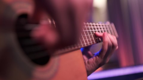 Close-up of a man's hands playing the guitar. The musician plays an acoustic guitar, closeup shot. Male fingers fast plays on guitar. human hands plays on a guitar neck, soft focus