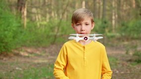 Child launches the drone outdoors. Boy plays with a quadrocopter on the nature. White boy is learning  to control a drone in the Park. Slow motion  video.