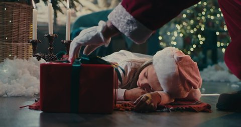 Crop Santa Claus exchanging letter for gift near sleeping girl at night during Christmas celebration