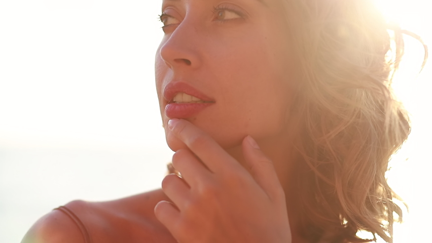 Young Smiling Attractive Girl Walks on Sea Shore at Beautiful Sunset Dusk in Sunshine Alone Close Up. Enjoying Carefree Tropical Relax, Inspiration Freedom, Travel Happiness, Evening Leisure Outdoors