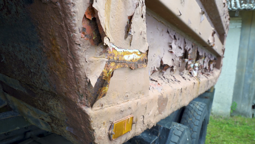 The peeling paint of the abandoned truck on the parking lot along with other vintage cars