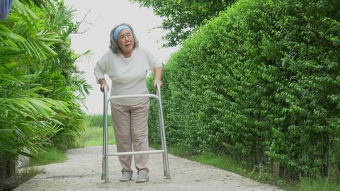 asian senior woman Suffering from walking with walker alone in back yard at home outdoors