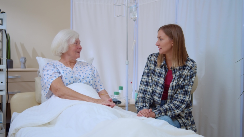 Happy young woman talking and supporting her mature mother patient sitting hospital room communicating about therapy healthcare family moments sharing love together. | Shutterstock HD Video #1062504610