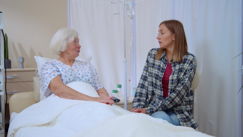 Hospitals. Family support. Positive young woman talking to elderly mother supporting sharing funny moments laughing communicating. Patients. Healthcare concept. | Shutterstock HD Video #1062504613