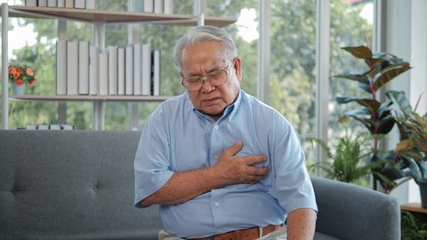 Elderly Asian man with chest pain suffering from heart attack. Man clutching his chest from acute pain. Heart attack symptom-Healthcare and medical concept.