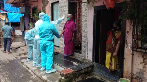 MUMBAI/INDIA- JUNE 17, 2020: Health workers wearing protective gear monitor body temperature of people during the health check up camp at Ramabai nagar slum.