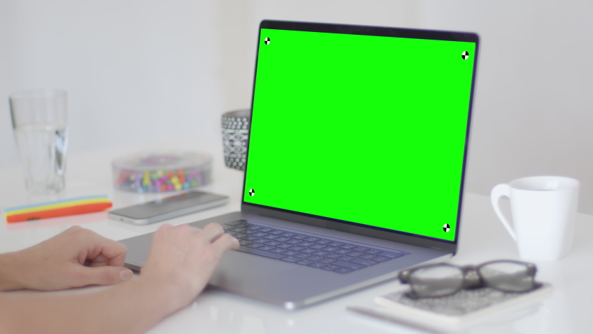 Woman hands using a laptop on a white desk. Colorful office elements in the background. Remote working. Perfect to put your own images or videos. Track points with perspective corner pin.    Royalty-Free Stock Footage #1062509248