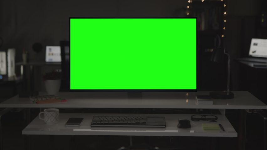 Green screen desktop computer on dark room. Several devices in the background.  Chroma key. Remote working. Home office. Put your own images or videos. Track corners with perspective corner pin. Royalty-Free Stock Footage #1062509251