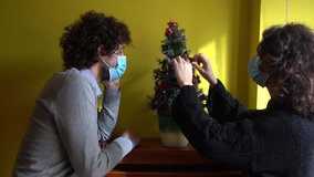 Europe, Italy , Milan - spend christmas alone away from home and family - couple with mask in the apartment,  lifestyle at home during lockdown , Covid-19 Coronavirus quarantine 