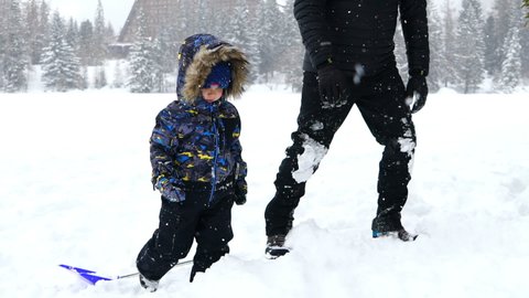 Man walking with his son in the snow covered field,  slow motion
