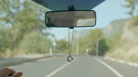 Moon star necklace hanging in the interior of the car in the rearview mirror