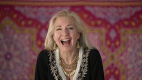 Portrait of a gorgeous blond haired ethnic woman laughing and smiling looking at camera in slow motion. Happy mature woman enjoys life.