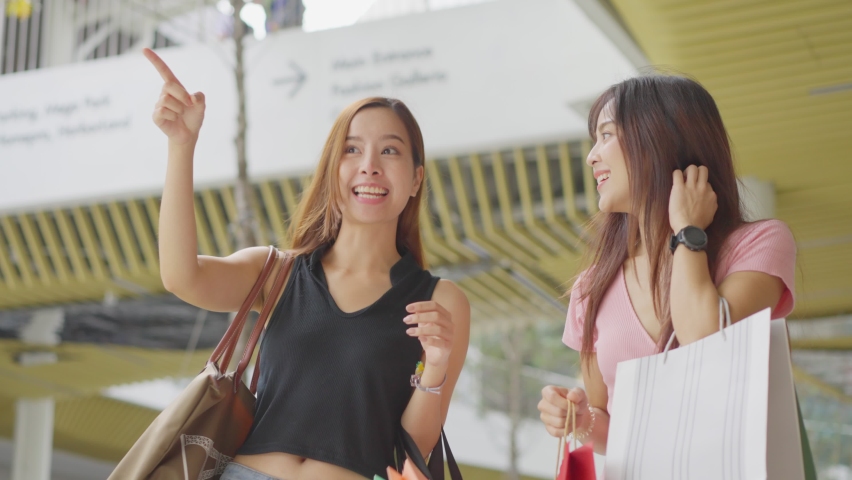 Two happy Asian young women shopping outdoor in department store during sale season at end of the year. The girls holding shopping bag walking with happiness and smile enjoy purchasing things together Royalty-Free Stock Footage #1062523777