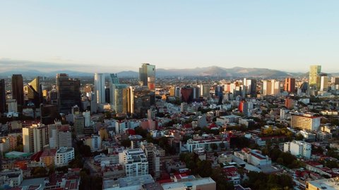 Aerial view towards buildings, in front of in the financial district, during sunset, in Chapultepec, Mexico city, Central America - tilt down,drone shot