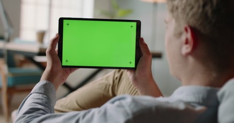 Close up shot of guy using a tablet computer with green mockup screen. Student during online lesson or work conference on self-isolation 4k footage