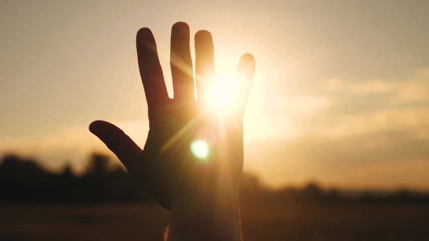 girl stretches out her hand in the sun. faith in god dream a religion concept. hand in the sun close-up sunlight silhouette dream of happiness Royalty-Free Stock Footage #1062527761