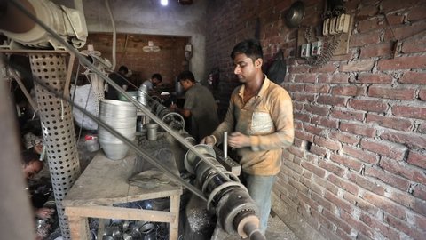 DHAKA, BANGLADESH - NOVEMBER 10, 2020: An industrial metal steel factory with people working in non compliance circumstances in a sweatshop to produce metal pots and pans