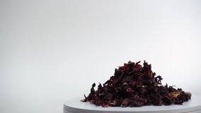 Leaves of hibiscus red dry tea on white background. Rotating video of Egyptian, Karkade tea on white table. Free space for text. Footage for 
product advertising. Studio light.