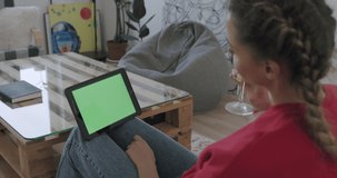Woman holding tablet computer with green screen while watching something. Chroma key. Female having glass of wine while chatting with friend or partner online. Stay home, quarantine concepte