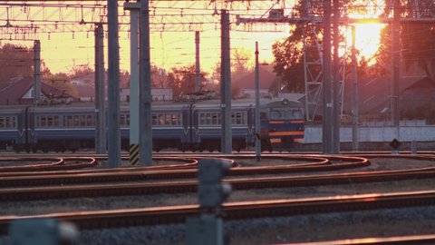 Russain passenger electric multiple unit train leaves the railway station at sunset. Passengers walk on the platform. Travel and tourism. Railroad carriage wagons going in daytime.